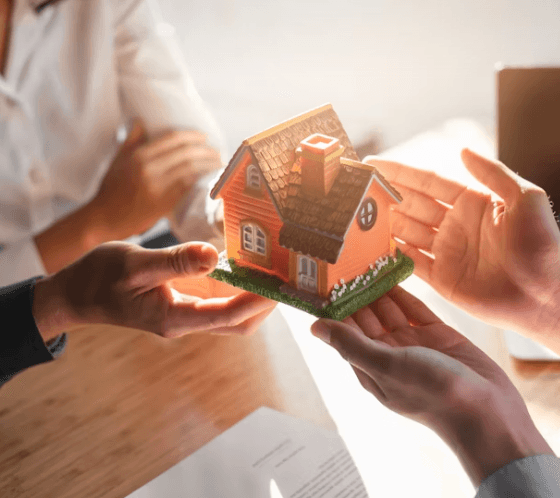 Real estate transaction - hands exchanging a house model representing property transfer